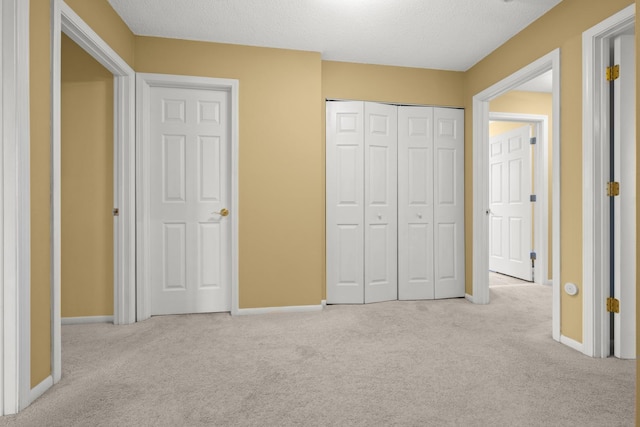 unfurnished bedroom featuring carpet flooring, a closet, a textured ceiling, and baseboards