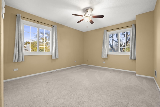 carpeted empty room featuring baseboards, a wealth of natural light, and a ceiling fan