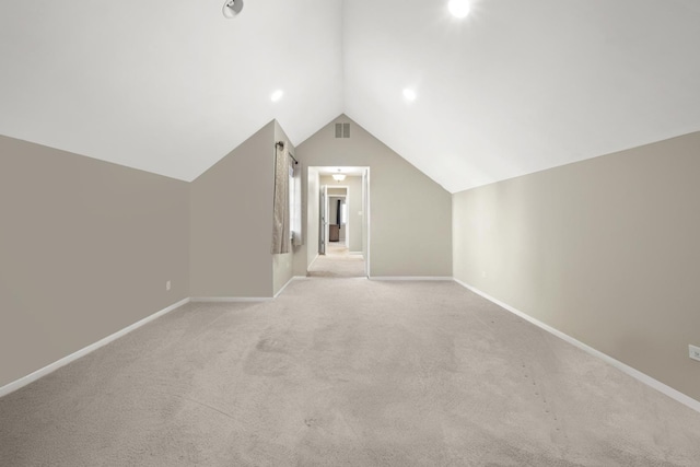 additional living space featuring baseboards, visible vents, light colored carpet, and vaulted ceiling