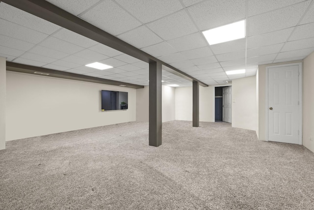 finished below grade area with a paneled ceiling and carpet flooring