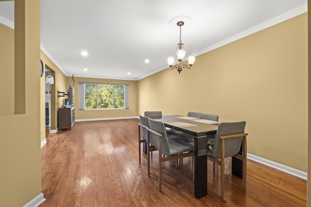 dining room featuring crown molding, wood finished floors, baseboards, and a notable chandelier