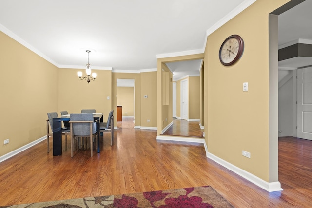 dining space with baseboards, an inviting chandelier, crown molding, and wood finished floors