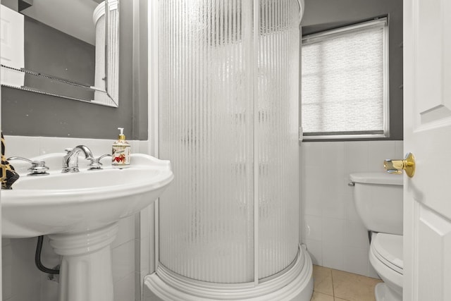 full bath with a stall shower, tile walls, tile patterned flooring, and toilet