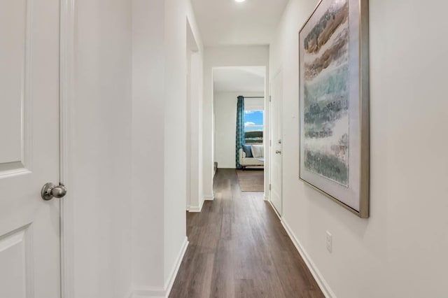 hallway with dark wood-type flooring and baseboards