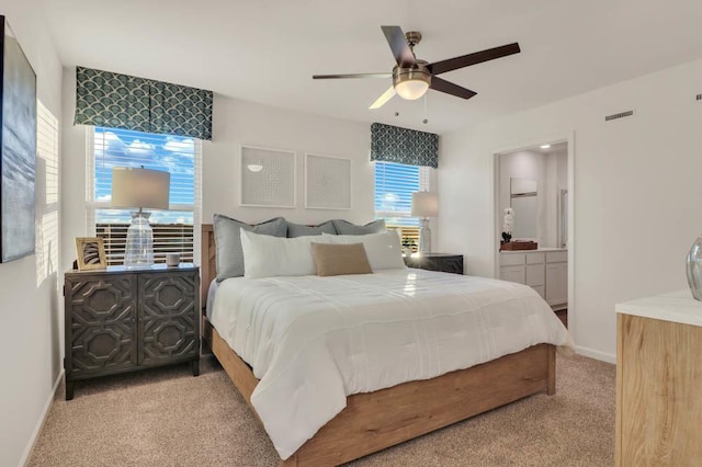 carpeted bedroom with ensuite bathroom, visible vents, baseboards, and a ceiling fan