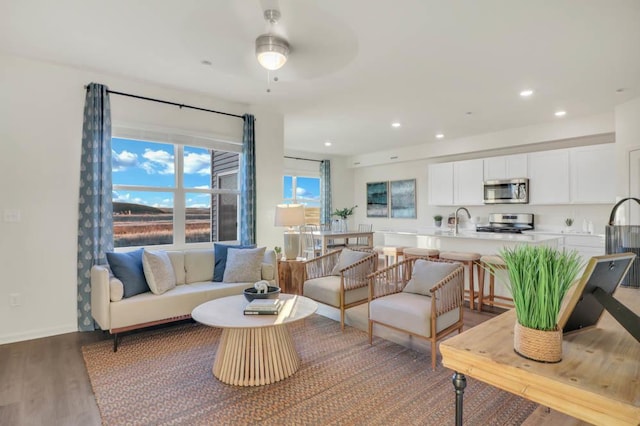 living room featuring a ceiling fan, baseboards, recessed lighting, and wood finished floors