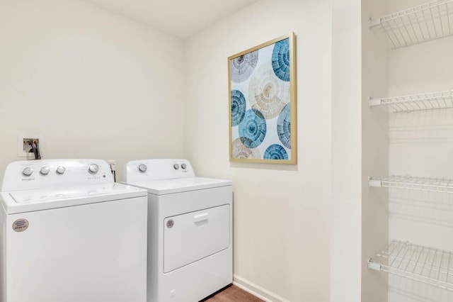 laundry area with washer and clothes dryer, laundry area, baseboards, and wood finished floors