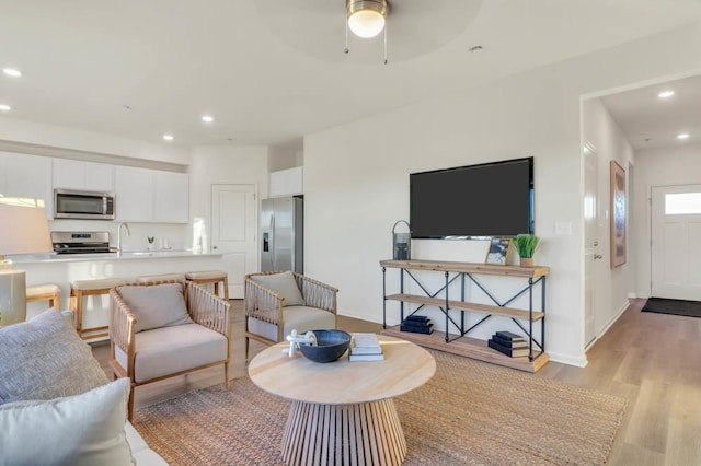 living room featuring recessed lighting, baseboards, a ceiling fan, and light wood-style floors