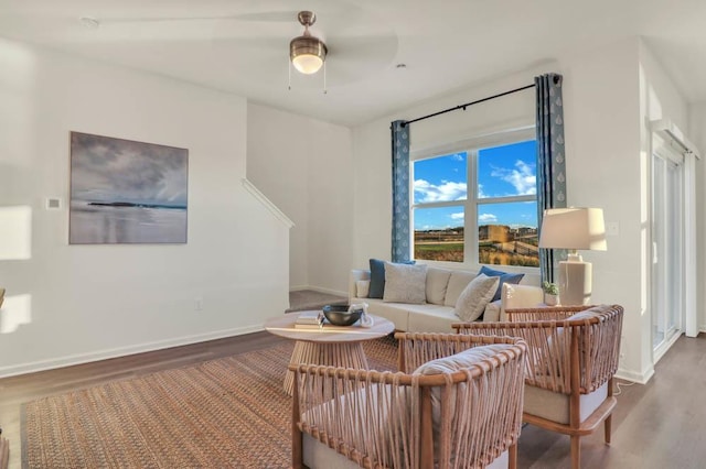 living area with baseboards, a ceiling fan, and wood finished floors
