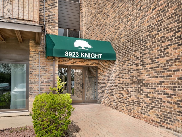 doorway to property featuring brick siding