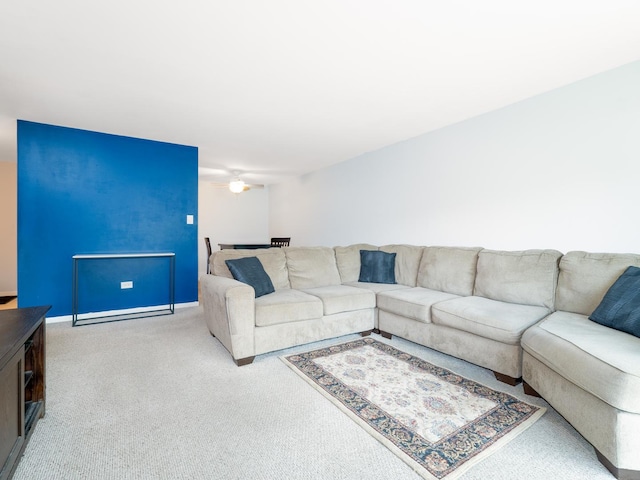carpeted living area with baseboards and a ceiling fan