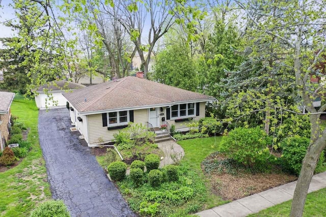 ranch-style house with an outdoor structure, a front lawn, and a shingled roof
