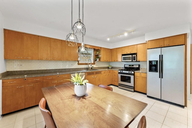 kitchen featuring stainless steel appliances, a sink, light tile patterned floors, and brown cabinetry