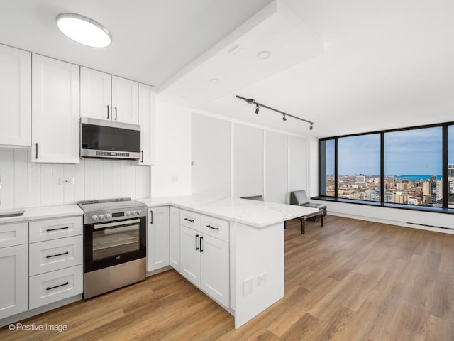 kitchen featuring light stone countertops, a peninsula, light wood-style floors, stainless steel appliances, and white cabinets