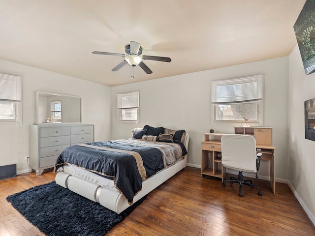 bedroom with baseboards, a ceiling fan, multiple windows, and wood finished floors