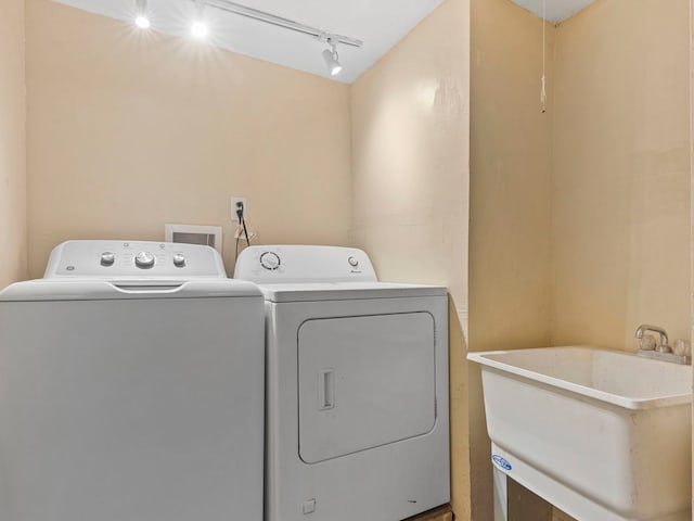 washroom with a sink, track lighting, laundry area, and independent washer and dryer