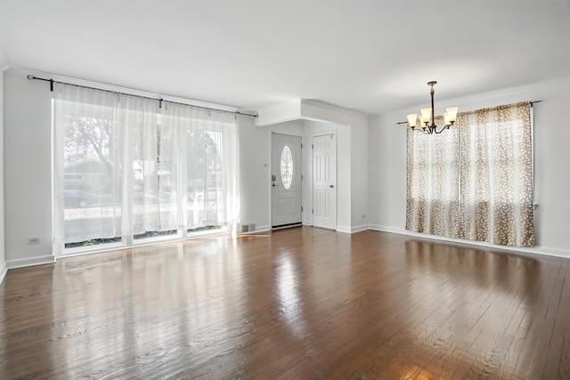 unfurnished living room featuring a chandelier, wood finished floors, and baseboards