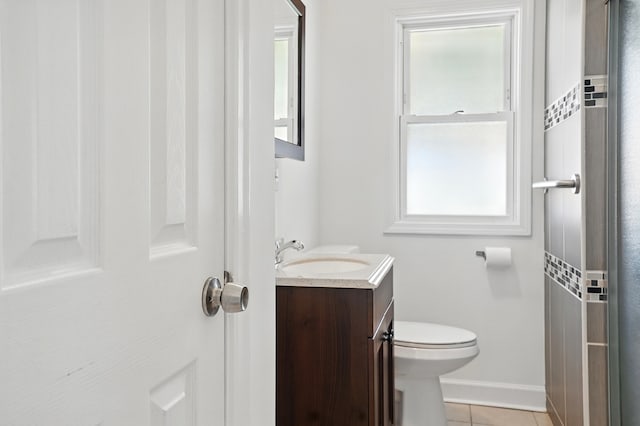bathroom with plenty of natural light, toilet, tile patterned flooring, and baseboards