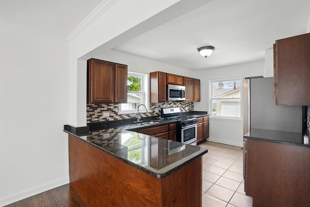 kitchen with stainless steel appliances, a sink, tasteful backsplash, baseboards, and crown molding