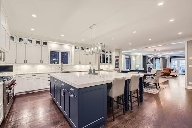 1955 N Halsted St Unit 1, Chicago, IL 60614 - kitchen with a chandelier, double oven range, white cabinets, a sink, and a kitchen island