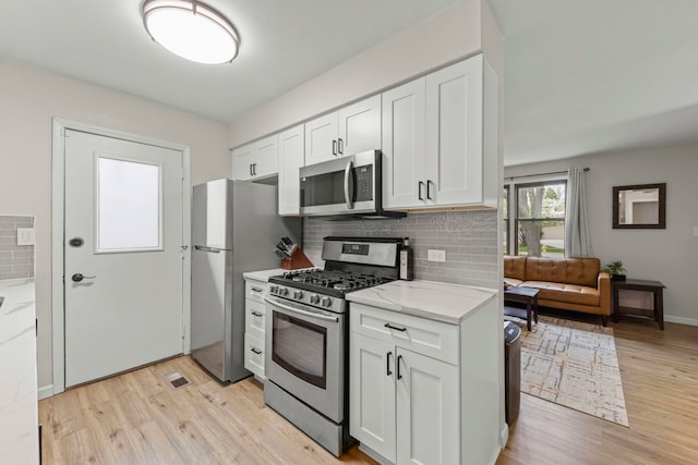 559 Coolidge Ave, Glen Ellyn, IL 60137 - kitchen featuring appliances with stainless steel finishes, light wood finished floors, backsplash, white cabinets, and light stone counters