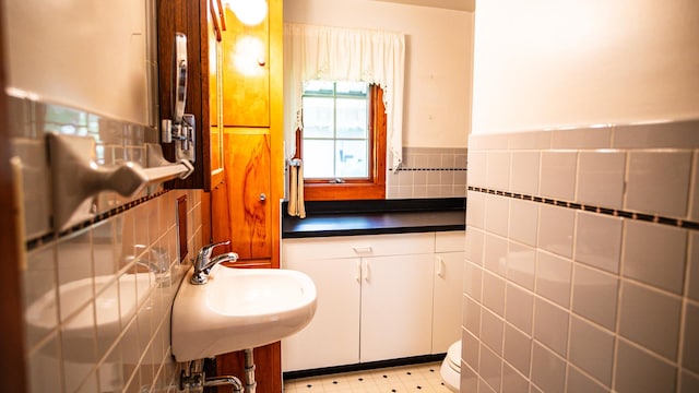 214 W Watson St, Forrest, IL 61741 - bathroom featuring tile walls, a sink, tile patterned floors, and wainscoting