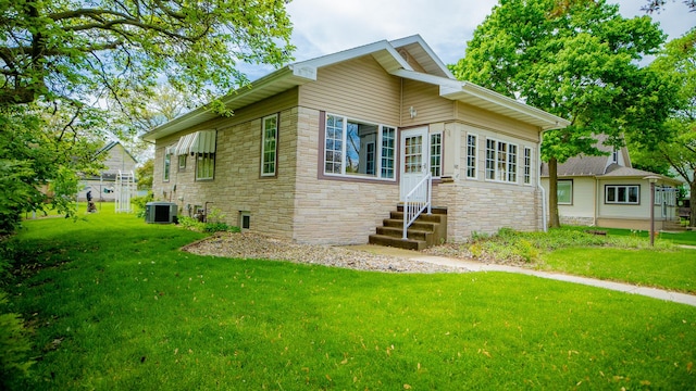 214 W Watson St, Forrest, IL 61741 - view of front of house with entry steps, stone siding, central air condition unit, and a front lawn
