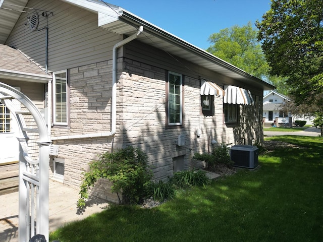 214 W Watson St, Forrest, IL 61741 - view of side of property featuring stone siding, central AC unit, and a yard