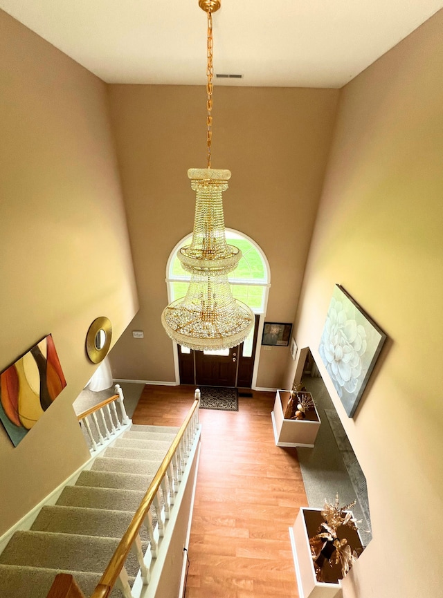 stairs featuring wood finished floors, baseboards, and a chandelier