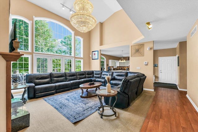 living room with a chandelier, baseboards, wood finished floors, a high ceiling, and rail lighting