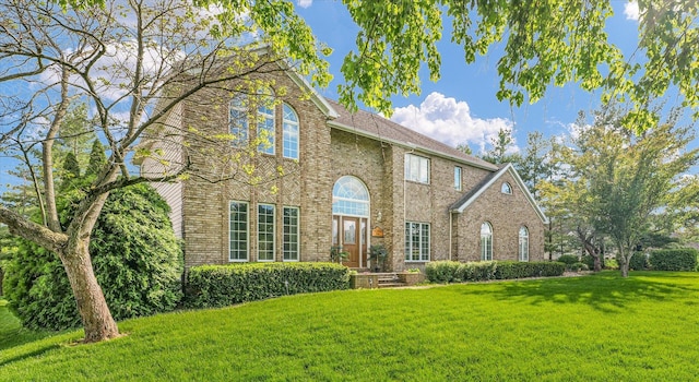colonial inspired home featuring a front yard and brick siding