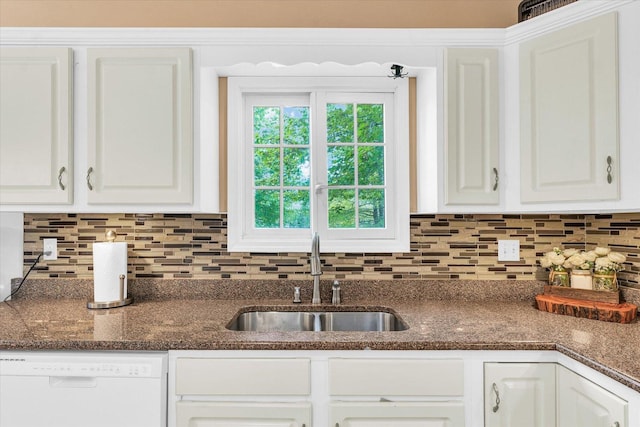 kitchen with white dishwasher, a sink, white cabinetry, and tasteful backsplash