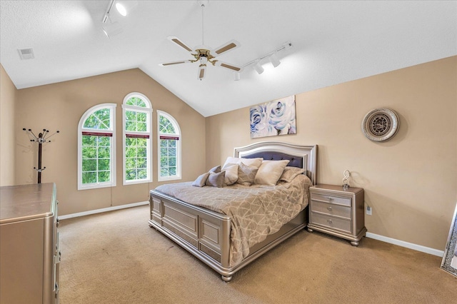 bedroom featuring rail lighting, light colored carpet, baseboards, vaulted ceiling, and a ceiling fan