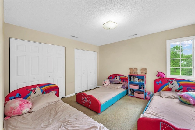carpeted bedroom with two closets and a textured ceiling