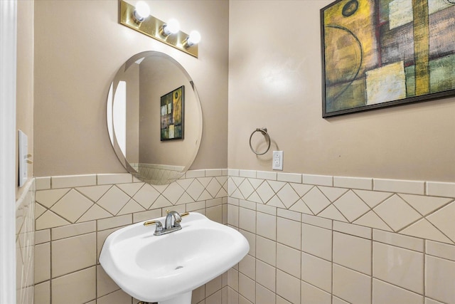 bathroom featuring a sink, wainscoting, and tile walls