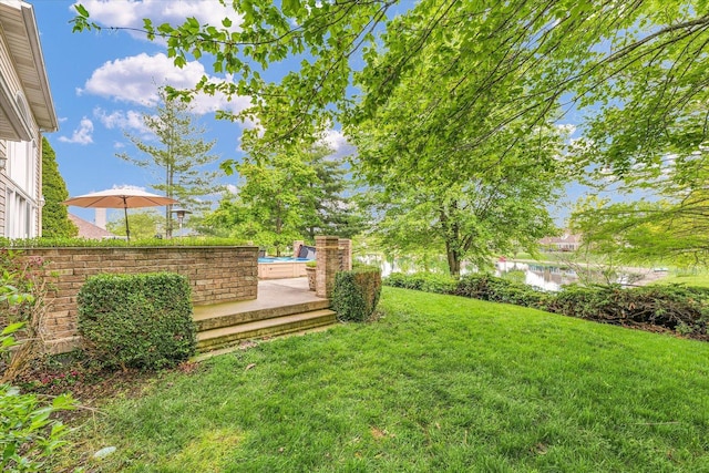 view of green lawn featuring a water view