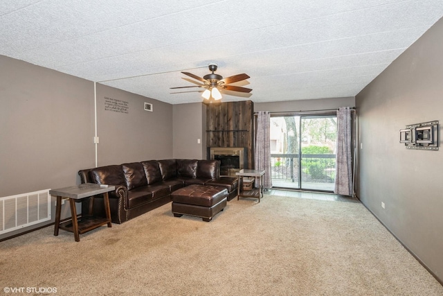 carpeted living area featuring ceiling fan, a fireplace, and visible vents
