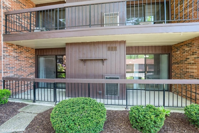 entrance to property with brick siding and a balcony