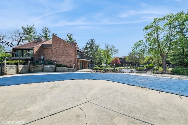 community pool with a patio area and fence