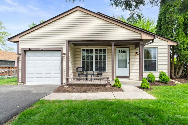 ranch-style home featuring covered porch, a garage, fence, aphalt driveway, and a front yard