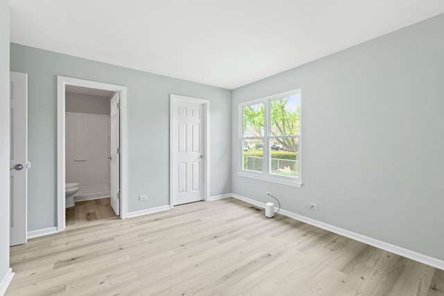 unfurnished bedroom with ensuite bath, baseboards, visible vents, and light wood-style floors