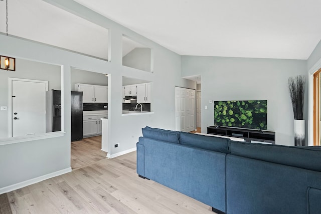 living room with light wood-type flooring, baseboards, and high vaulted ceiling