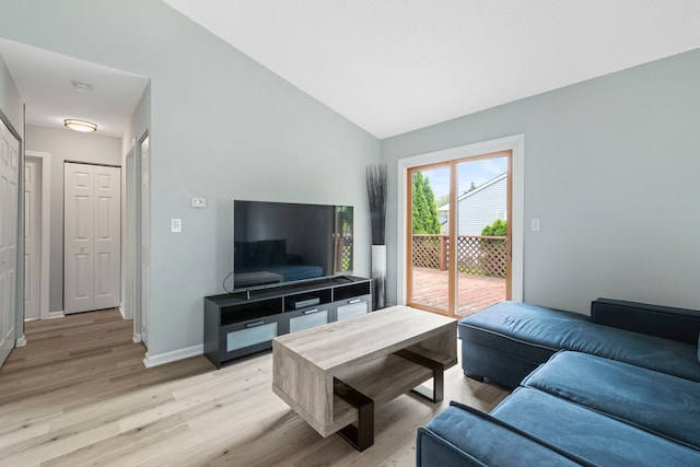 living room with vaulted ceiling, light wood-style flooring, and baseboards