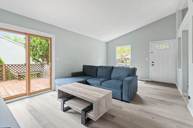 living room featuring light wood finished floors, vaulted ceiling, and baseboards
