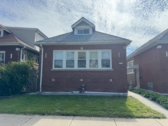 view of front facade with brick siding and a front yard