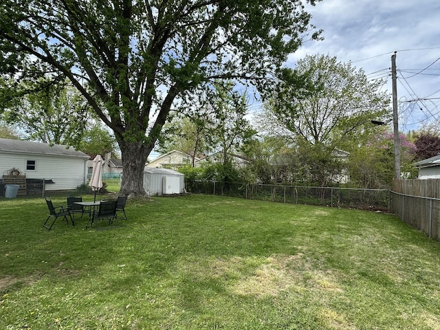 view of yard with an outdoor structure, a fenced backyard, and a shed
