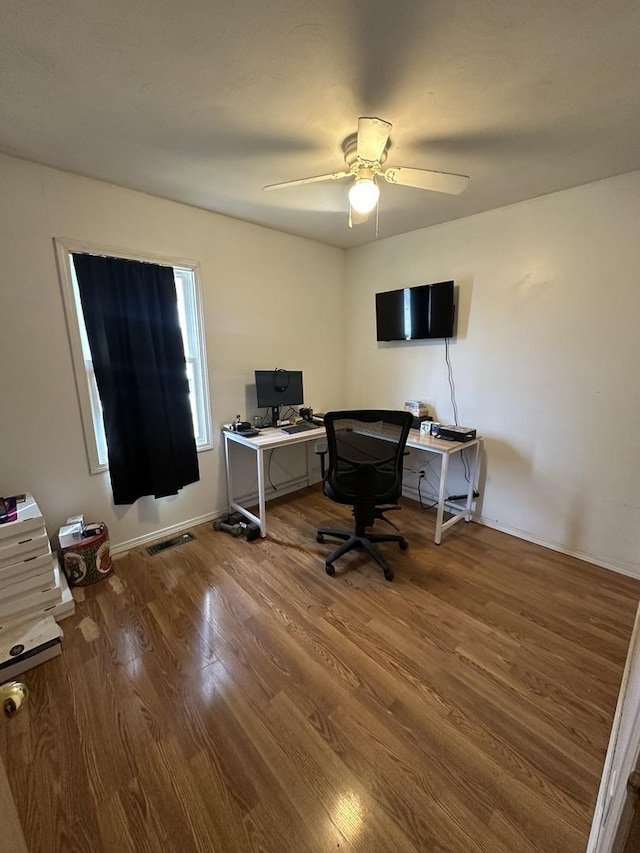 office area featuring baseboards, a ceiling fan, visible vents, and wood finished floors