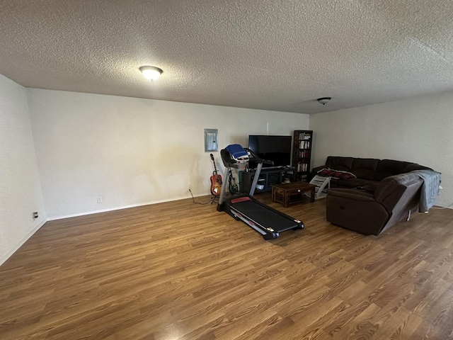 exercise room featuring electric panel, a textured ceiling, and wood finished floors