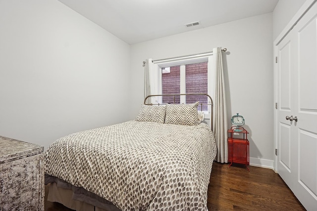 bedroom with baseboards, visible vents, and wood finished floors