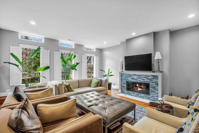 living room with wood finished floors, baseboards, a fireplace, and recessed lighting